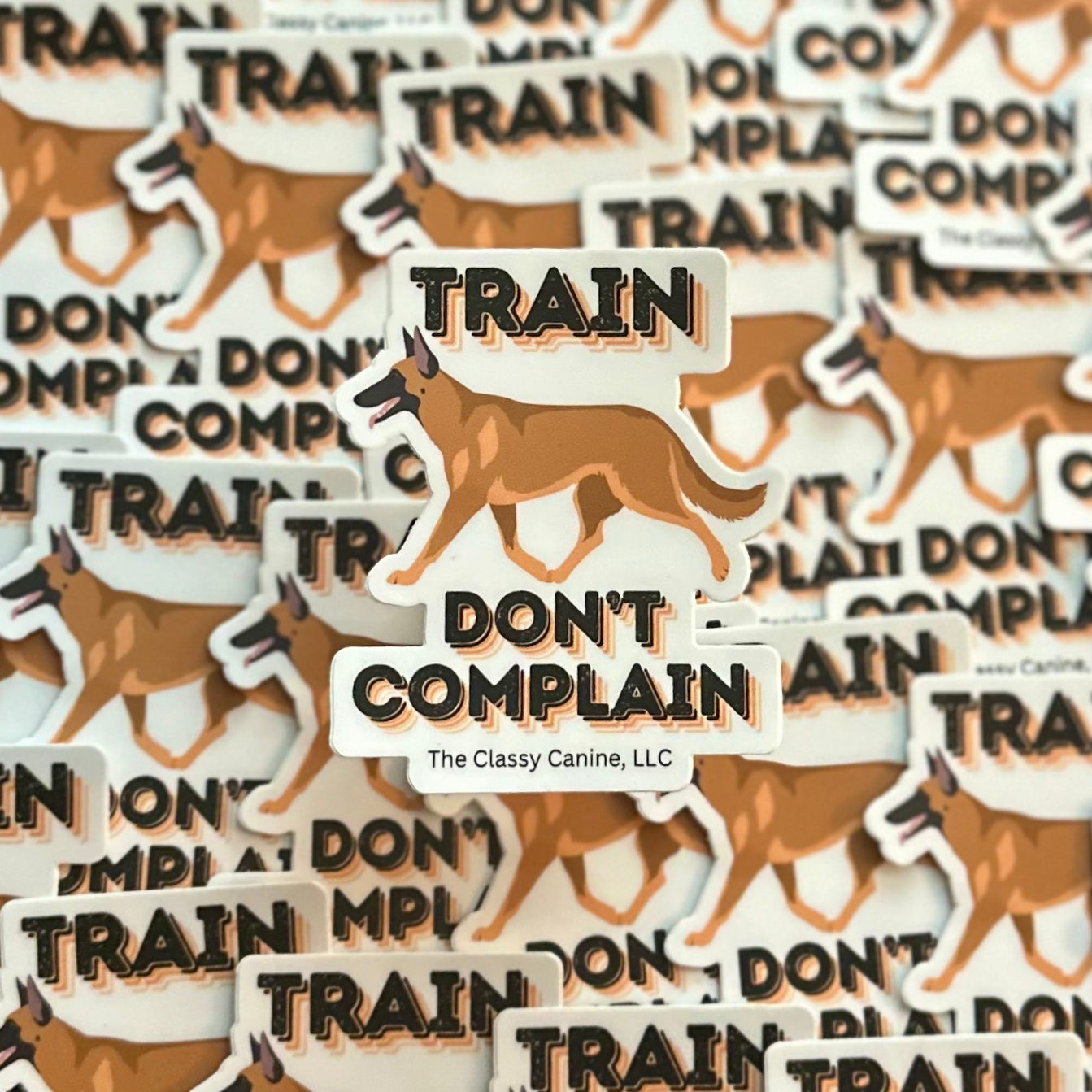 Train Don’t Complain Belgian Malinois Sticker 2.54" x 3" – durable vinyl dog decal for working dog enthusiasts, laptops, cars, and water bottles.